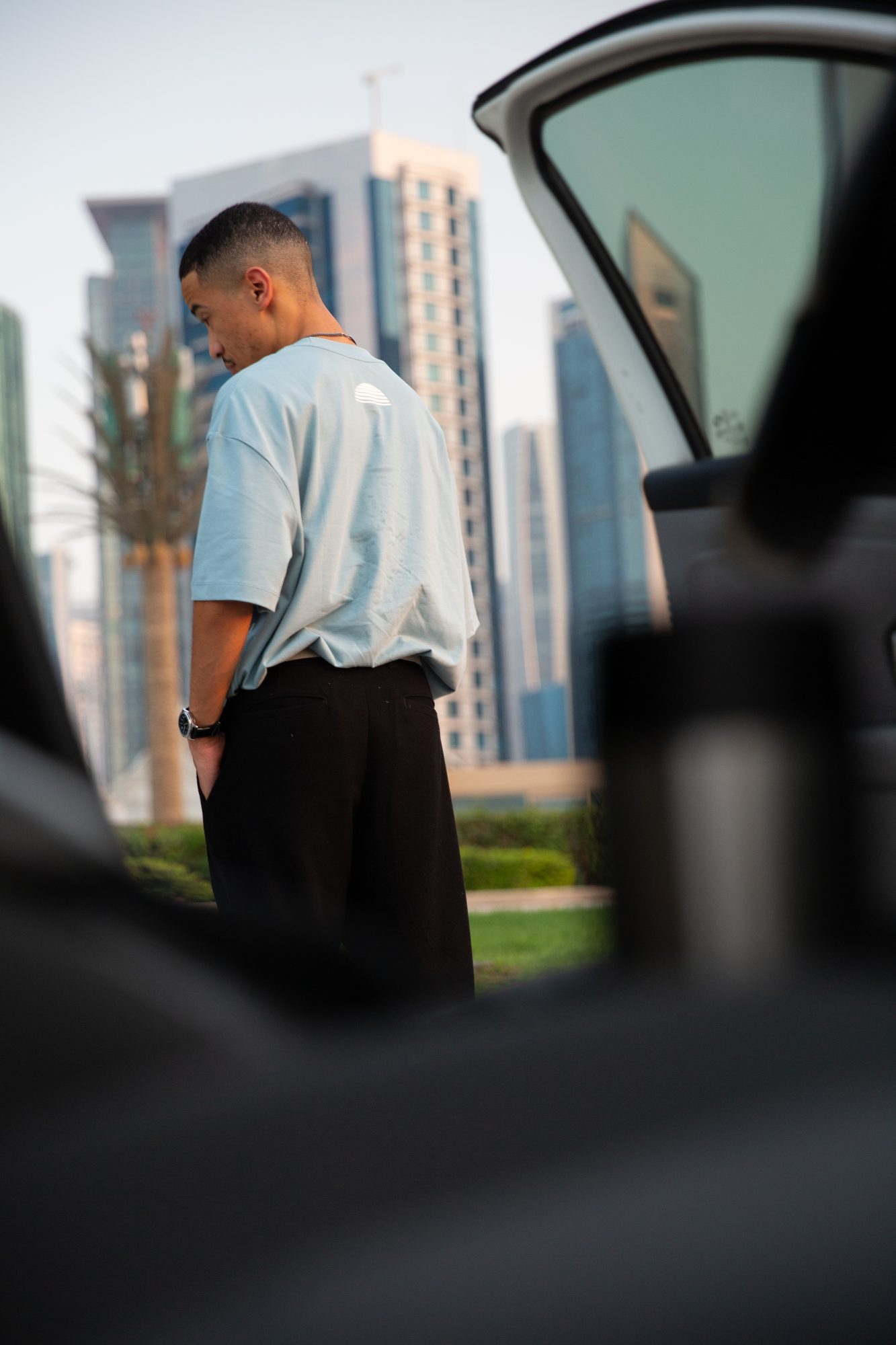 Model framed through an open car door against glass towers
